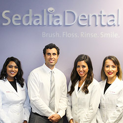 Dentists posing below Sedalia Dental sign