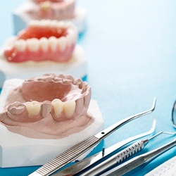 models of dentures sitting next to dental tools