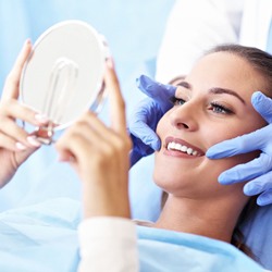 A female patient smiling while a dentist points to the corners of her mouth