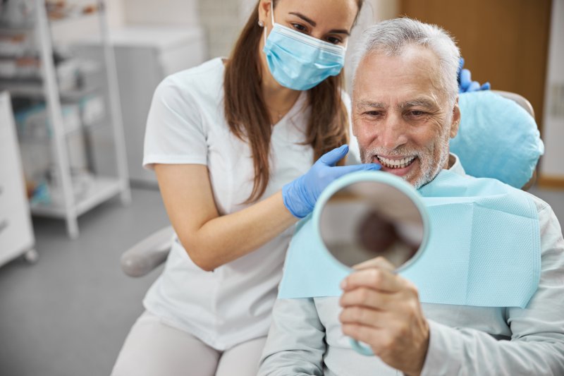 An older man looking at his new dental implants